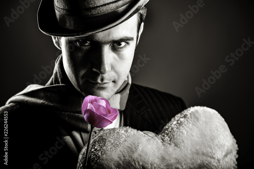Mysterious men with toy and rose on grey background. Image on black and white color