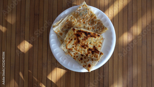 Top view of a plate with Turkish food Gözleme. A plate with traditional pancakes Gözleme revolves against the background of a wooden table.