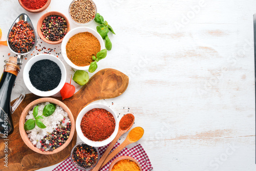 A set of Spices and herbs on a white wooden table. Basil, pepper, saffron, spices. Indian traditional cuisine. Top view. Free copy space.