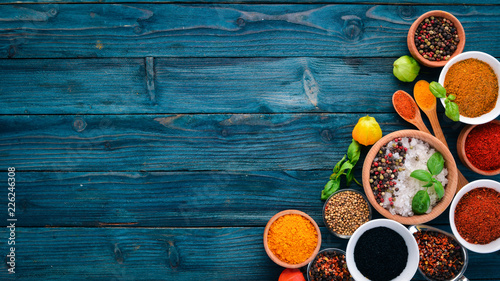 Fototapeta Naklejka Na Ścianę i Meble -  Spices and herbs on a blue wooden table. Basil, pepper, saffron, spices. Indian traditional cuisine. Top view. Free copy space.