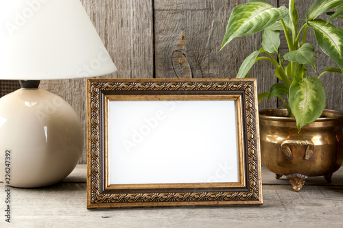 Empty brass picture frame on wooden background.
