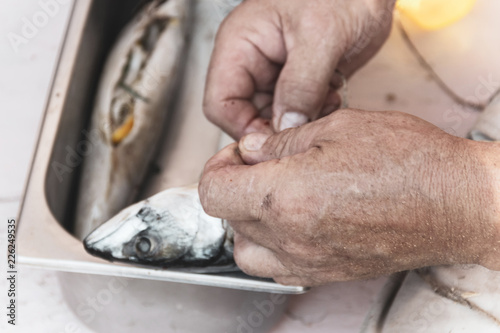 how to smoke fish at home. Male hands wrapping mackerel before smoking