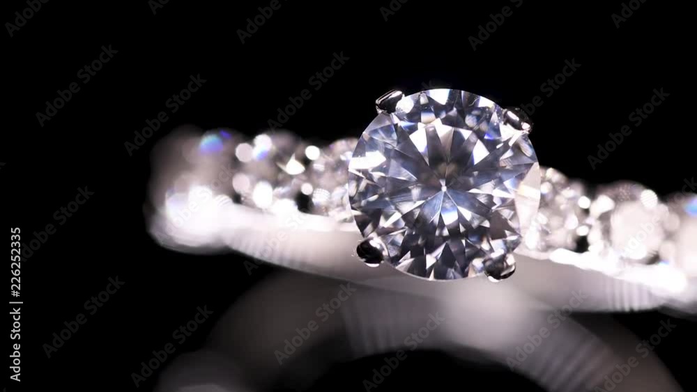 Engagement diamond ring rotating on black background, macro with shallow DoF