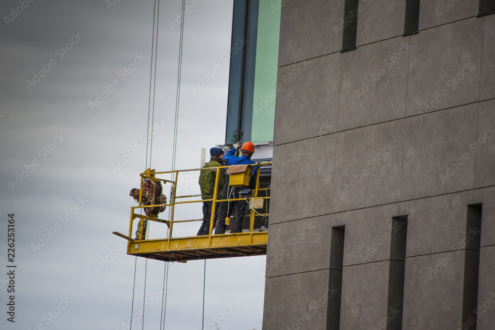 Naklejka premium construction worker on a scaffold, symbol photo for building, construction boom, labor protection