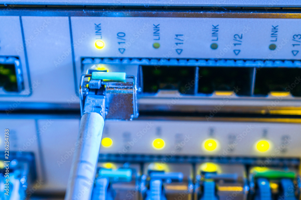 The fiber optic cable is connected to the SFP module of the central server.  The concept of high-speed Internet connection. Selective focus. Green  indication of optical links of the main router Stock