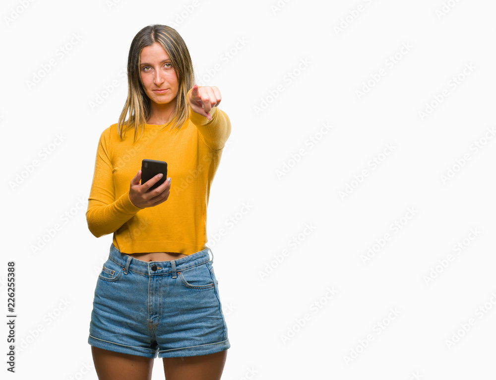 Young beautiful woman sending message using smartphone over isolated background pointing with finger to the camera and to you, hand sign, positive and confident gesture from the front