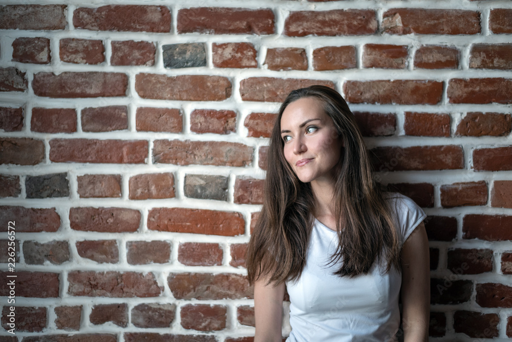 Brunette on red brick wall background looking away, copy space Brunette on red brick wall background looking away, copy space