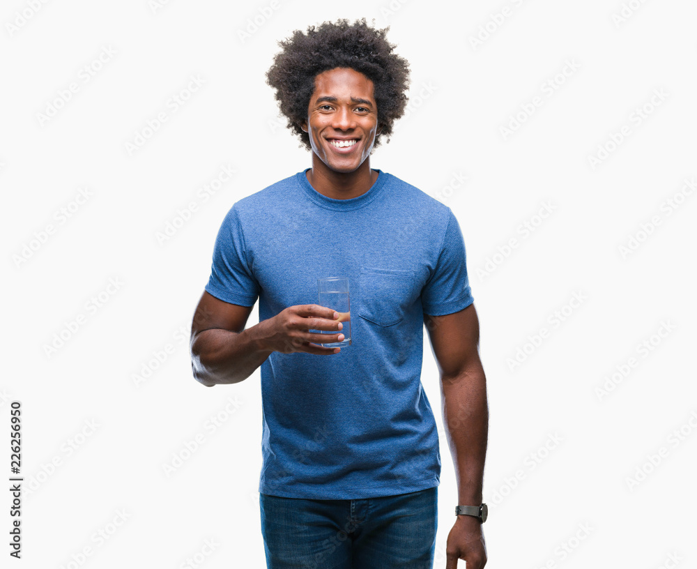 Afro american man drinking glass of water over isolated background with a happy face standing and smiling with a confident smile showing teeth Afro american man drinking glass of water over isolated background with a happy face standing and smiling with a confident smile showing teeth