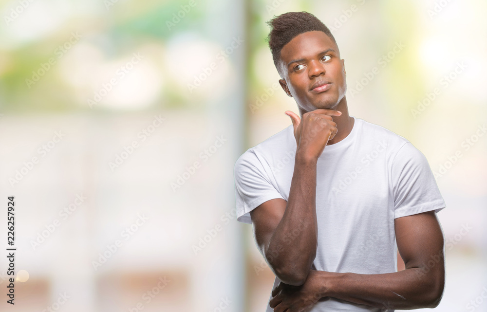 Obraz premium Young african american man over isolated background with hand on chin thinking about question, pensive expression. Smiling with thoughtful face. Doubt concept.