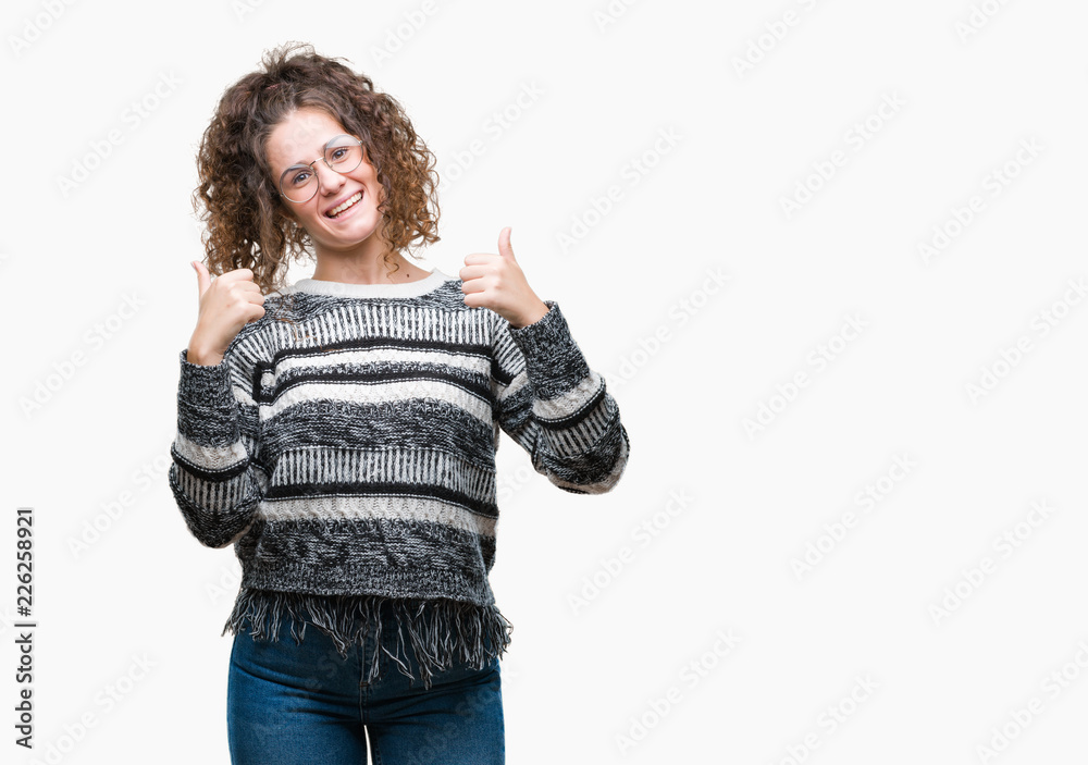 Beautiful brunette curly hair young girl wearing glasses over isolated background success sign doing positive gesture with hand, thumbs up smiling and happy. Looking at the camera Beautiful brunette curly hair young girl wearing glasses over isolated background success sign doing positive gesture with hand, thumbs up smiling and happy. Looking at the camera
