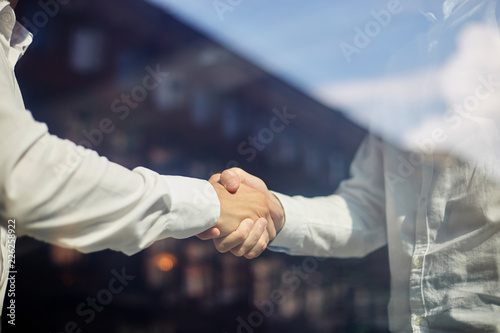 Crop businessmen shaking hands in sunlight