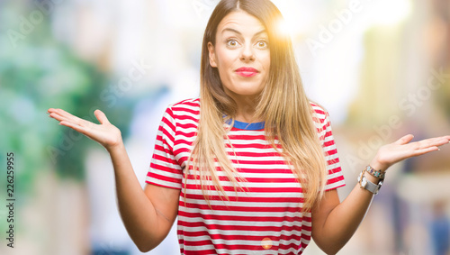 Young beautiful woman casual look over isolated background clueless and confused expression with arms and hands raised. Doubt concept.