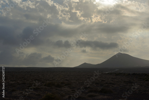 Grey clouds over desert and volcano in dusk