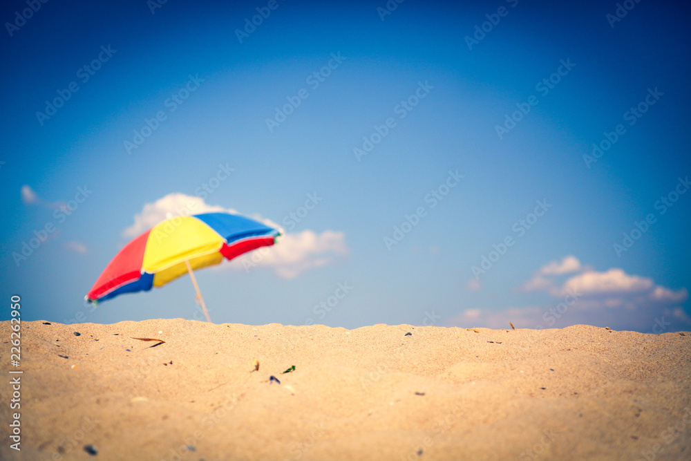View and sand with colorful umbrella on background. Summer season