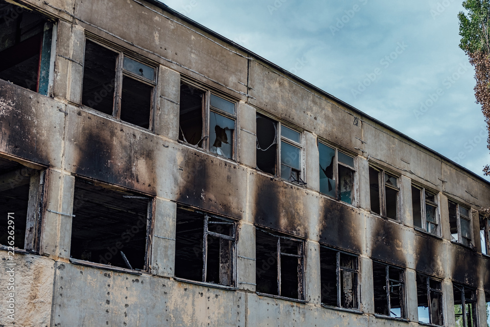 Consequences of fire. Burnt industrial or office building. Broken windows, walls in black soot