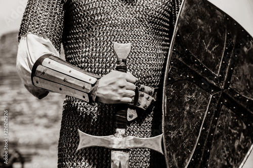 Knight man holding sword and shield. Image in black and white color style photo