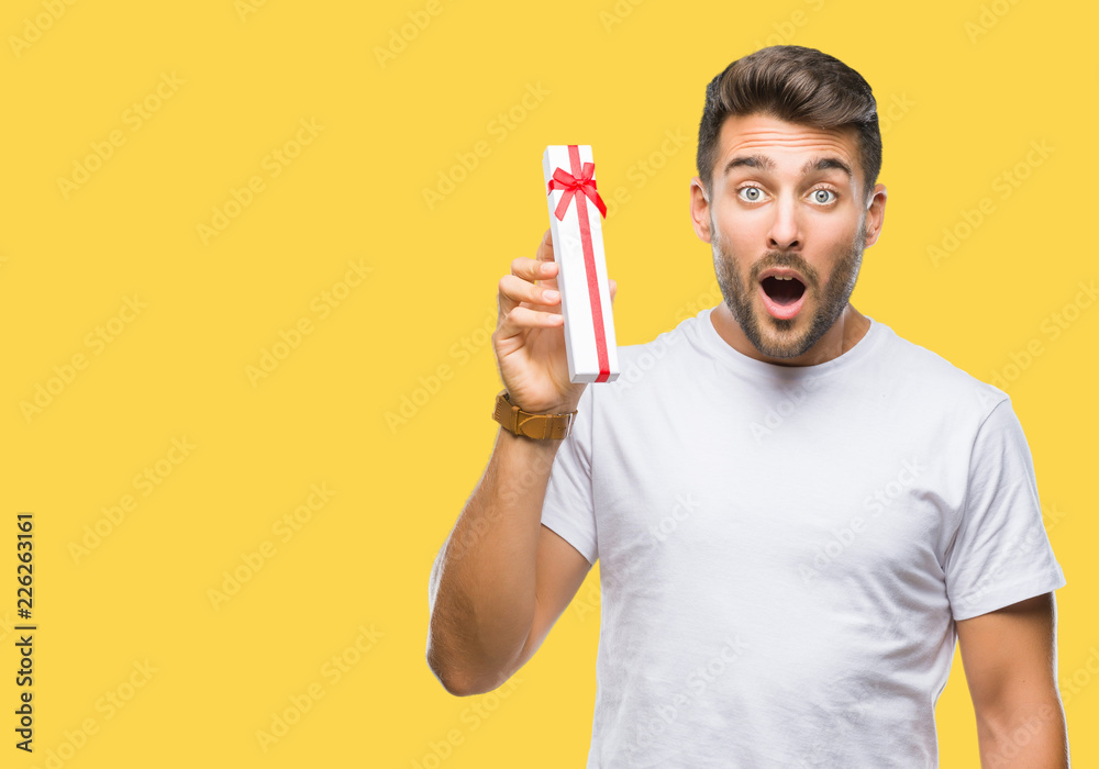 Young handsome man in love giving valentine present over isolated background scared in shock with a surprise face, afraid and excited with fear expression Young handsome man in love giving valentine present over isolated background scared in shock with a surprise face, afraid and excited with fear expression