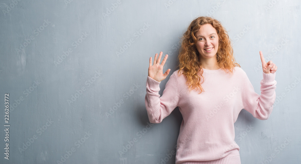 Φωτογραφία Young redhead woman over grey grunge wall wearing pink sweater showing and pointing up with fingers number six while smiling confident and happy