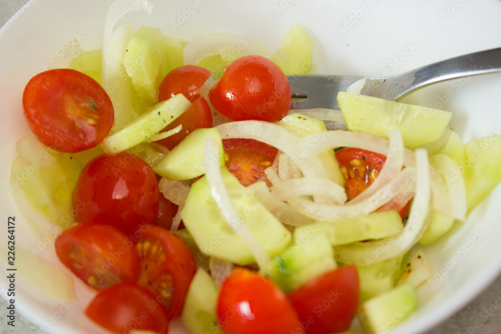 chopped vegetables tomatoes cucumbers and onions in a white plate