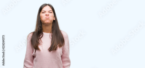 Vászonkép Young beautiful hispanic woman wearing a sweater puffing cheeks with funny face
