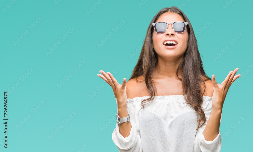 Young beautiful arab woman wearing sunglasses over isolated background crazy and mad shouting and yelling with aggressive expression and arms raised. Frustration concept. Young beautiful arab woman wearing sunglasses over isolated background crazy and mad shouting and yelling with aggressive expression and arms raised. Frustration concept.
