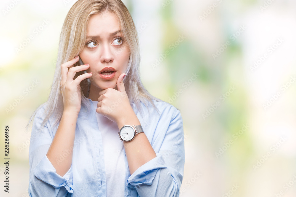 Young blonde woman talking using smarpthone over isolated background serious face thinking about question, very confused idea Young blonde woman talking using smarpthone over isolated background serious face thinking about question, very confused idea