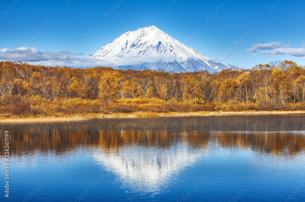 Panoramic autumn view of the Koryaksky Volcano reflected in the water of the lake. Russian Far East, Kamchatka Peninsula Panoramic autumn view of the Koryaksky Volcano reflected in the water of the lake. Russian Far East, Kamchatka Peninsula