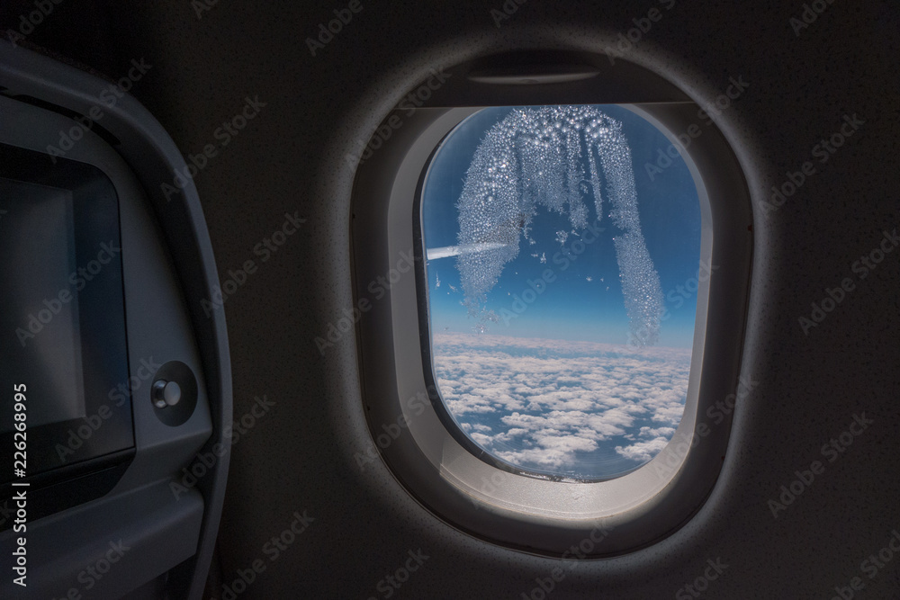 Frozen condensation in the window of an airplane with the wing in the back. Frozen condensation in the window of an airplane with the wing in the back.