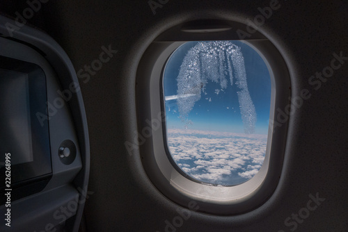 Frozen condensation in the window of an airplane with the wing in the back.
