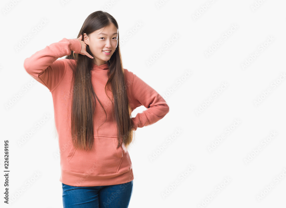 Young Chinese woman over isolated background wearing sport sweathshirt smiling doing phone gesture with hand and fingers like talking on the telephone. Communicating concepts. Young Chinese woman over isolated background wearing sport sweathshirt smiling doing phone gesture with hand and fingers like talking on the telephone. Communicating concepts.