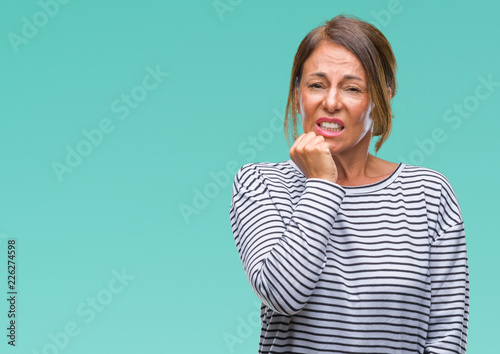 Middle age senior hispanic woman over isolated background looking stressed and nervous with hands on mouth biting nails. Anxiety problem.