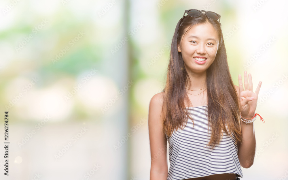 Young asian woman wearing sunglasses over isolated background showing and pointing up with fingers number four while smiling confident and happy.