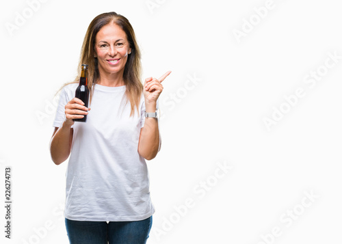 Middle age hispanic woman drinking beer over isolated background very happy pointing with hand and finger to the side