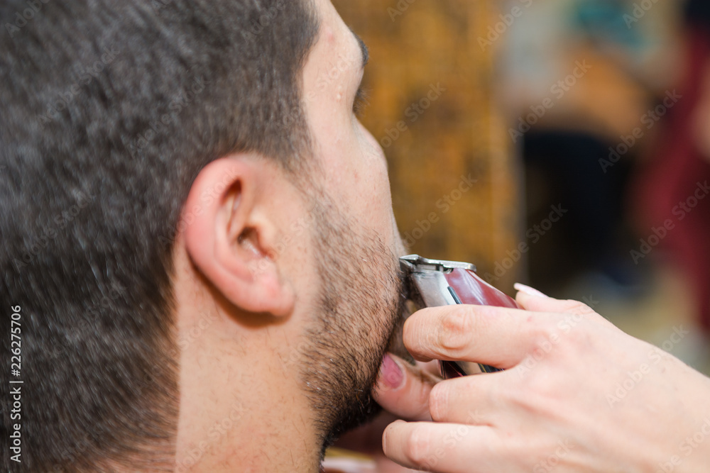 Shaving a beard to a man in a beauty salon with a typewriter Shaving a beard to a man in a beauty salon with a typewriter