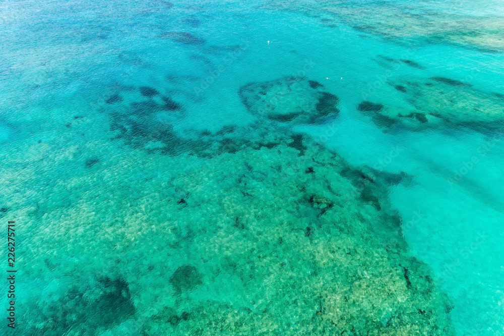 Aerial view of clear ocean water with colar reefs. Nature summer background