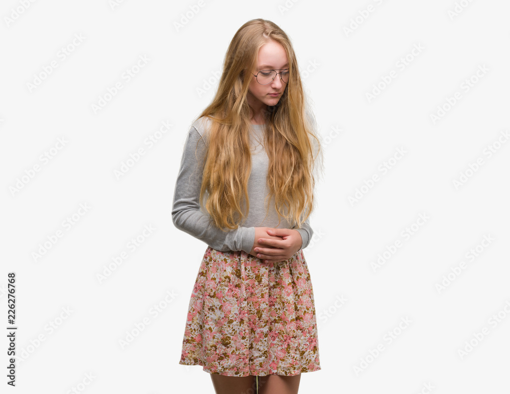 Blonde teenager woman wearing flowers skirt with hand on stomach because nausea, painful disease feeling unwell. Ache concept. Blonde teenager woman wearing flowers skirt with hand on stomach because nausea, painful disease feeling unwell. Ache concept.