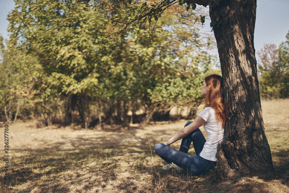 Naklejka premium woman sitting on the ground leaning on a tree