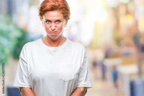 Atrractive senior caucasian redhead woman over isolated background puffing cheeks with funny face. Mouth inflated with air, crazy expression.