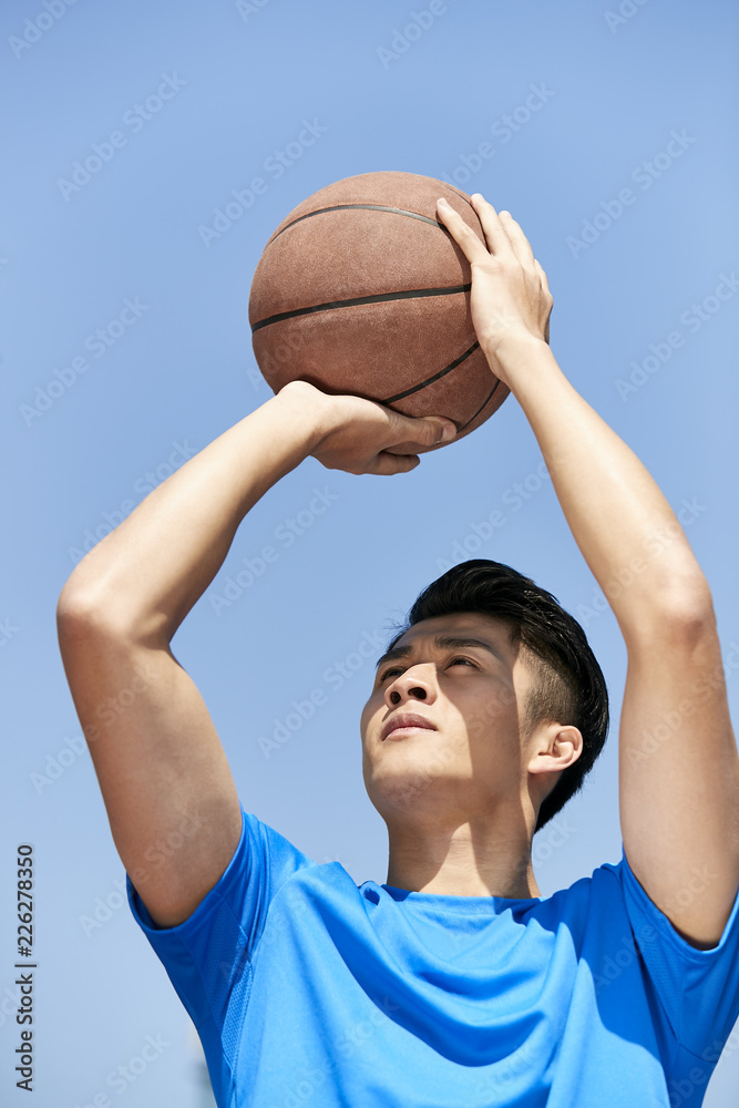 Obraz premium young asian basketball player making jump shot