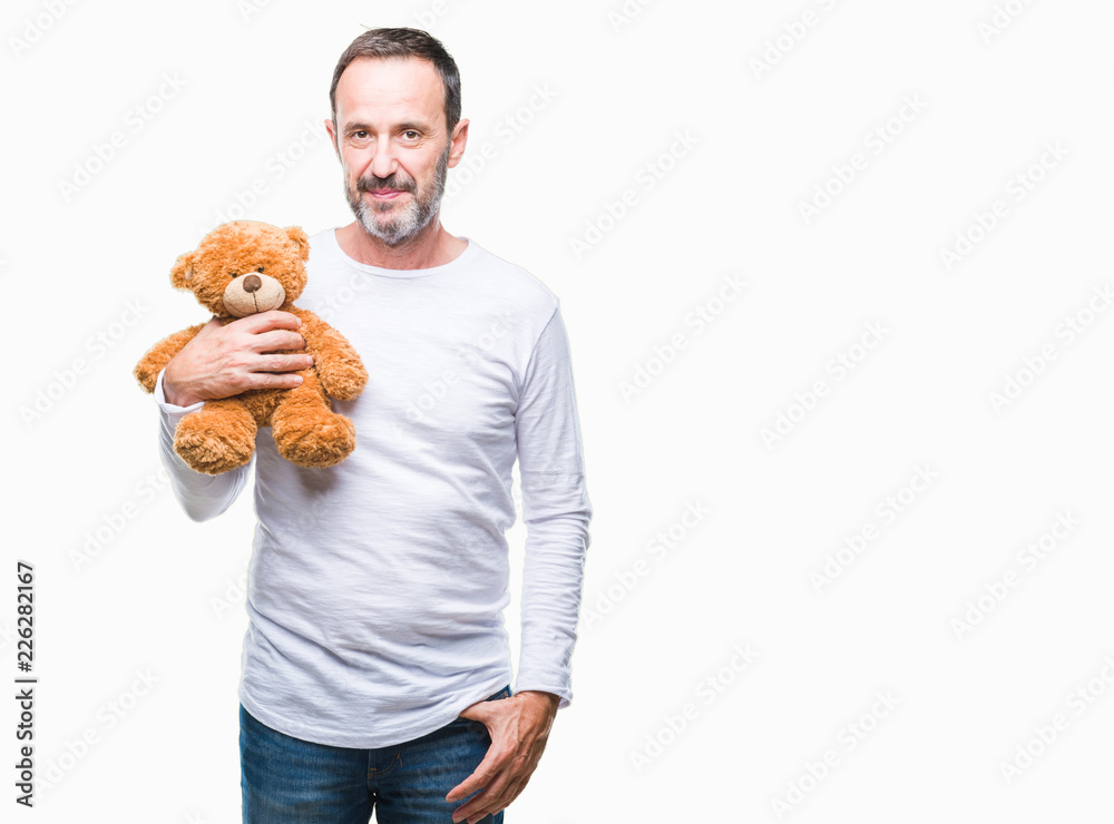 Middle age senior hoary man holding teddy bear over isolated background with a confident expression on smart face thinking serious Middle age senior hoary man holding teddy bear over isolated background with a confident expression on smart face thinking serious