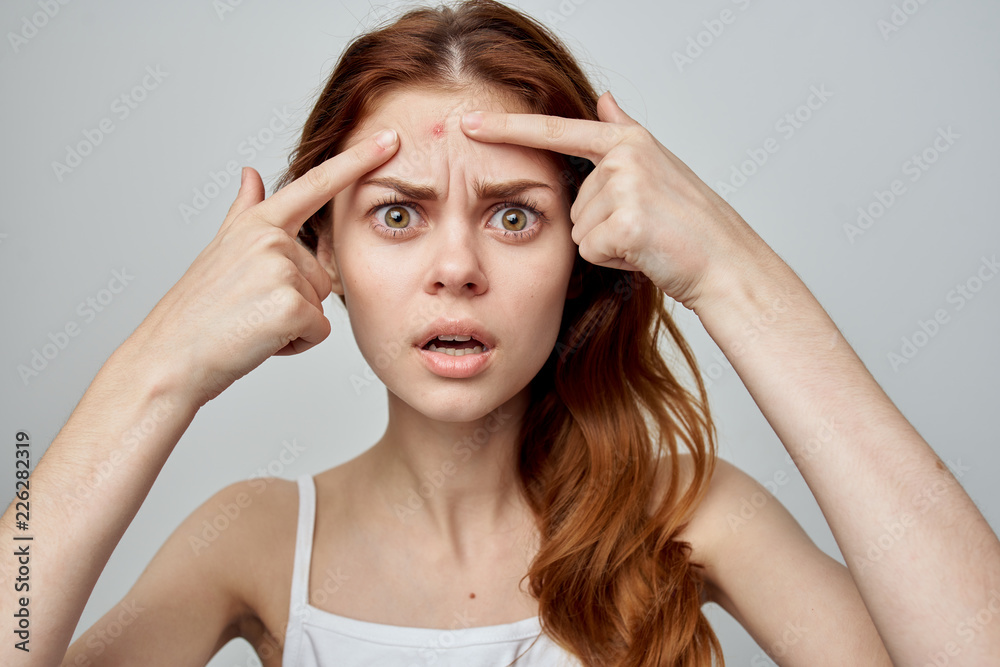 surprised woman holds fingers near a pimple surprised woman holds fingers near a pimple