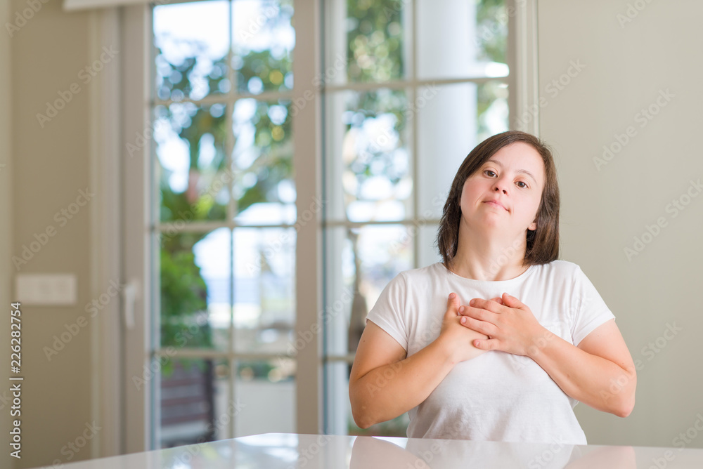Down syndrome woman at home smiling with hands on chest with closed eyes and grateful gesture on face. Health concept. Down syndrome woman at home smiling with hands on chest with closed eyes and grateful gesture on face. Health concept.
