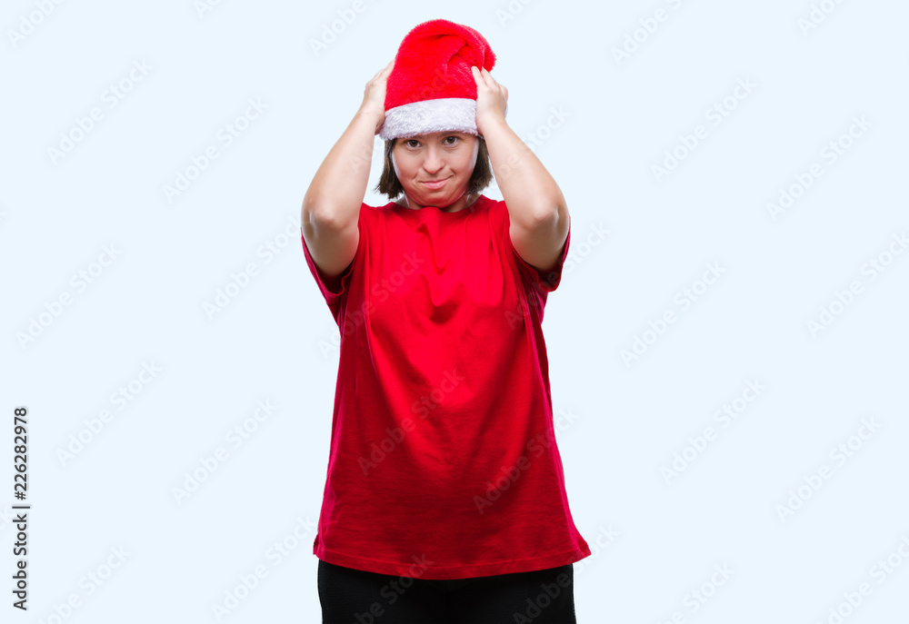 Young adult woman with down syndrome wearing christmas hat over isolated background suffering from headache desperate and stressed because pain and migraine. Hands on head. Young adult woman with down syndrome wearing christmas hat over isolated background suffering from headache desperate and stressed because pain and migraine. Hands on head.