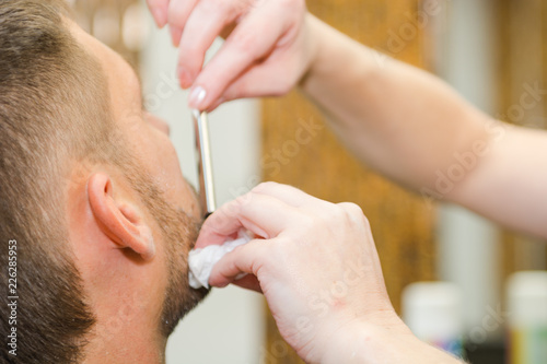 Shave a man's beard with a straight razor