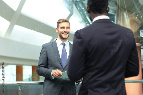 Two multinational young businessmen discussing business at meeting in office.