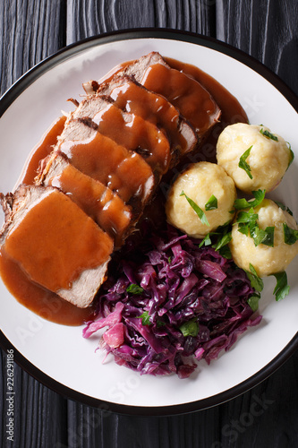German roast pot Sauerbraten served with potato dumplings and red cabbage close-up. Vertical top view