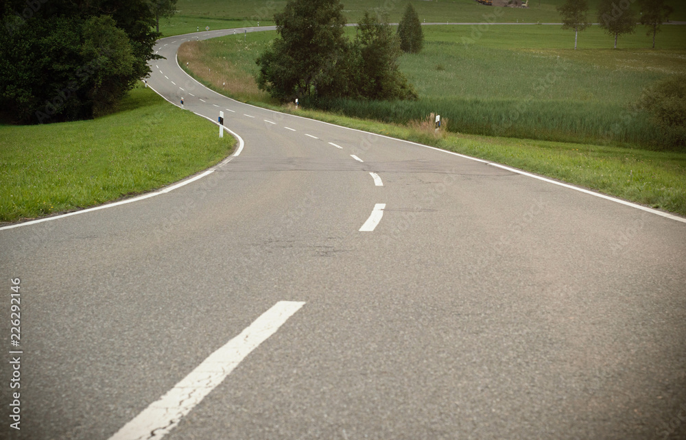 A winding asphalt road. Cross lines on road, Close up view of a road in curves