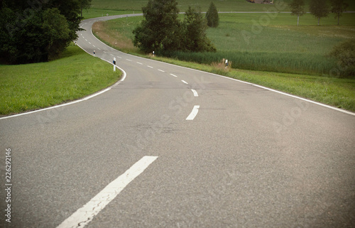 A winding asphalt road. Cross lines on road, Close up view of a road in curves