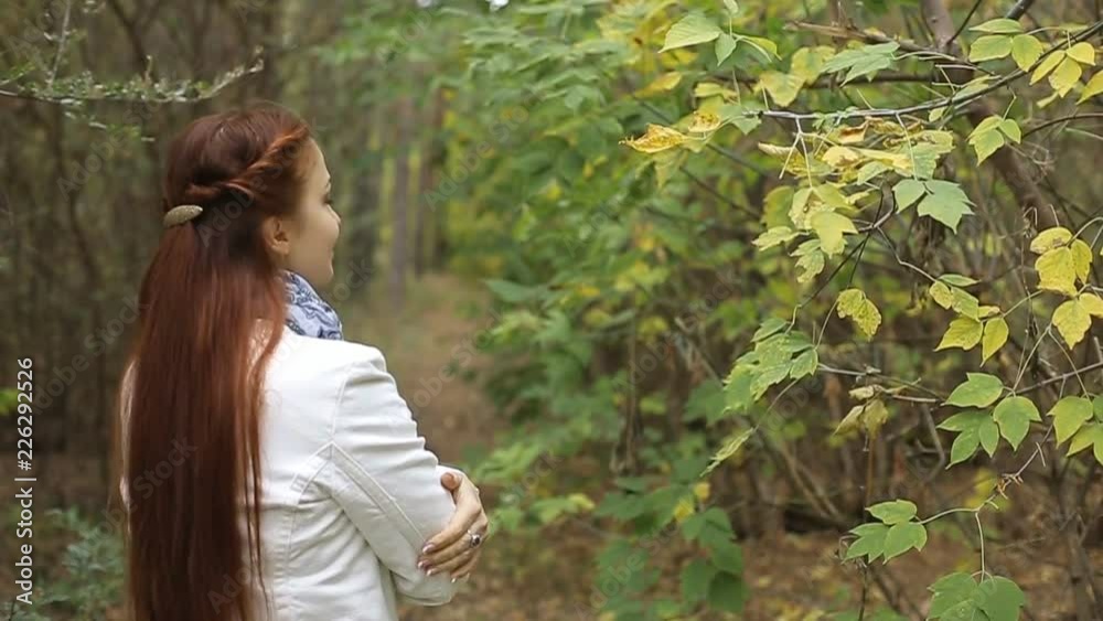 red-haired Caucasian middle-aged woman in a white coat walks on a cloudy day in the autumn park red-haired Caucasian middle-aged woman in a white coat walks on a cloudy day in the autumn park