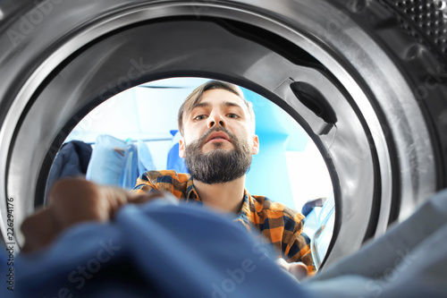 Fotografija Man doing laundry in laundromat, view from the inside of washing machine